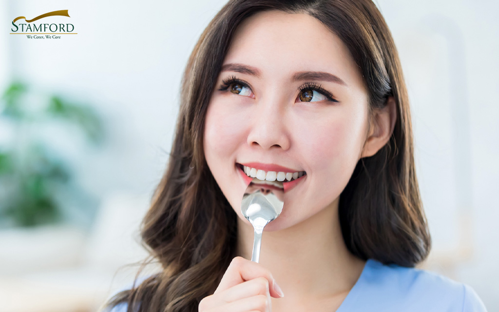 Image of a woman holding a spoon in her mouth