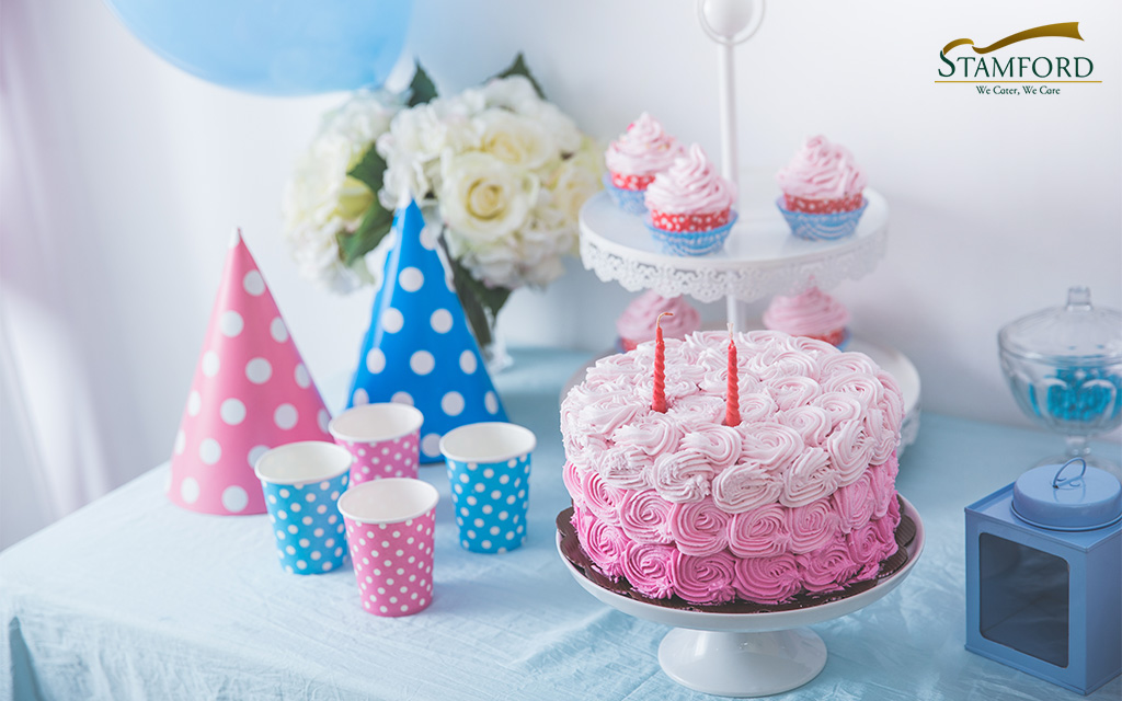 Pink birthday cake and party decorations.