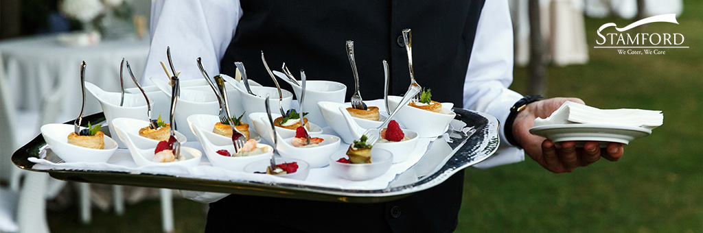 Server carrying a tray of elegant wedding canapés.